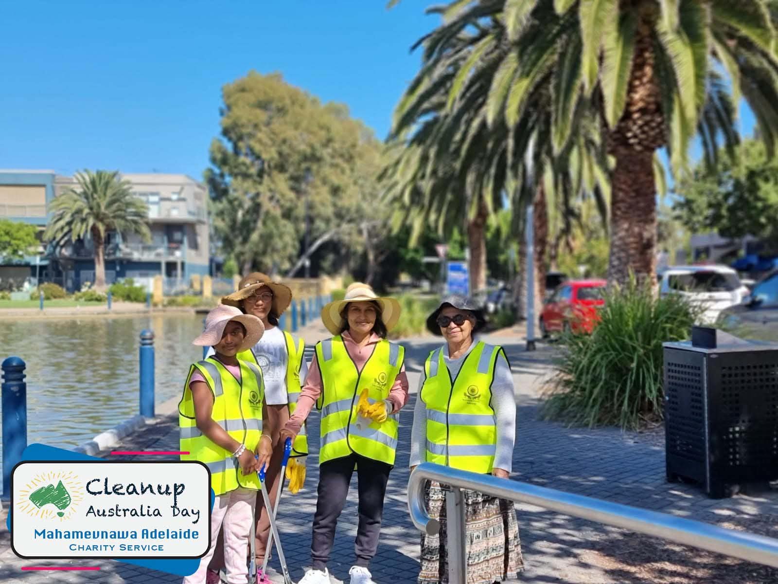 Women in high-visibility vests standing beside a waterfront during a community cleanup.